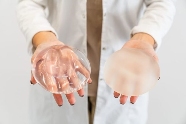 A doctor holding two types of breast implants