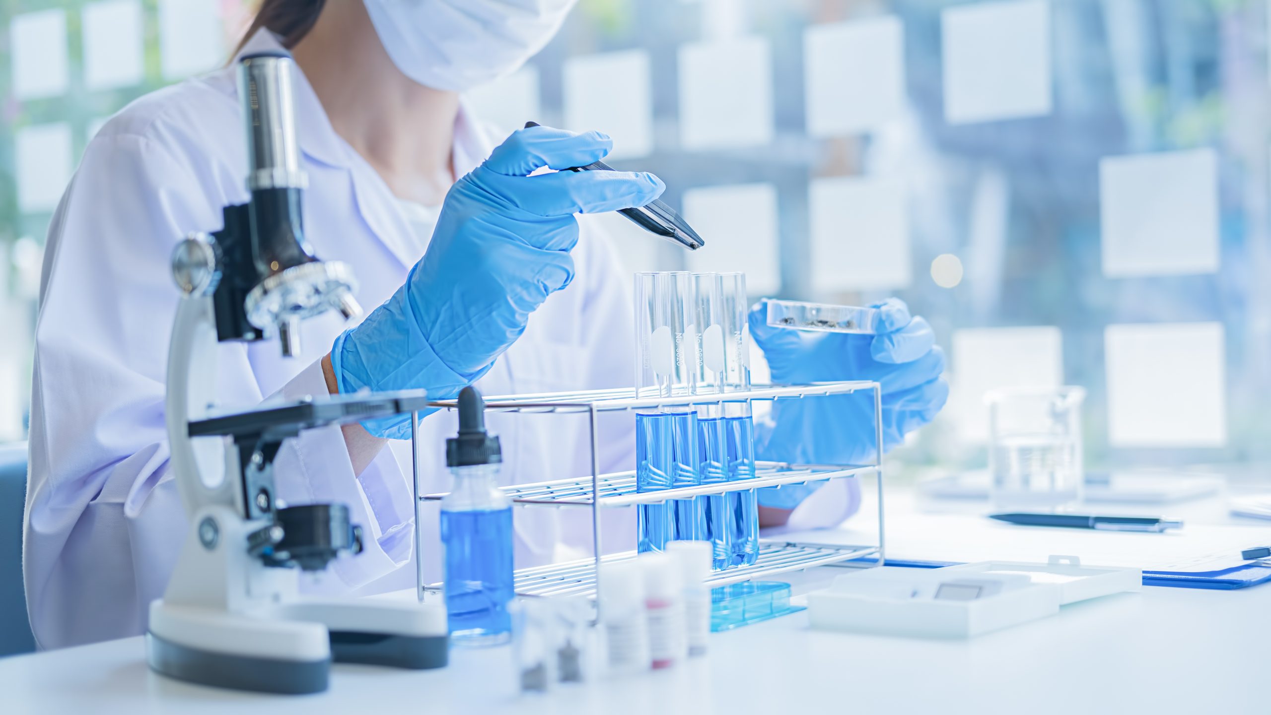 Technician looking at a test tube of clear solution in a laboratory